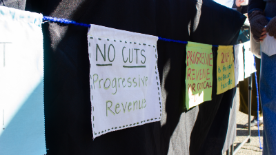 A handmade sign reads "No Cuts! Progressive revenue"